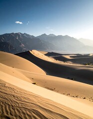 Desert dunes meet distant mountains under a vast, clear sky