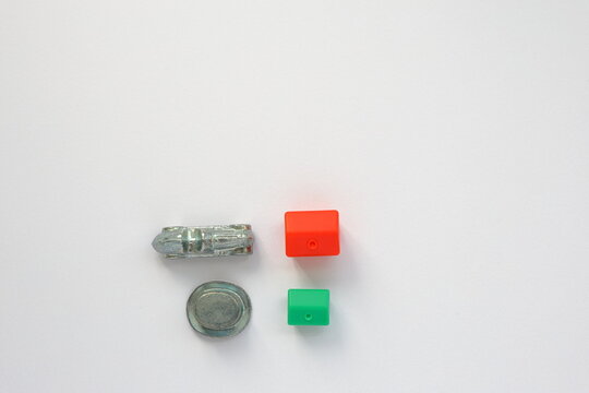 Monopoly game pieces. Car and hat token with red hotel and green house. Above angle shot photo.