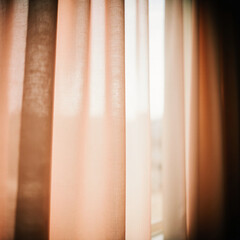 Fototapeta premium Silky curtains in beige and peach blend smoothly, allowing soft sunlight to enter a welcoming room. This cozy setting feels calm and serene in the afternoon light Generative AI