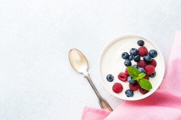 Yogurt with fresh berries in white bowl.