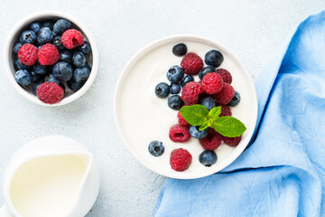 Yogurt with fresh berries in white bowl.