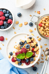 Yogurt with fresh berries and granola on white table.