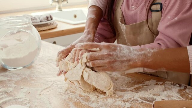 In a warm kitchen, a mother and daughter share a moment of joy as they knead dough together. Flour dusts the wooden surface, showcasing their bond and love for baking.