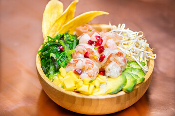 Poke bowl colorata con ingredienti freschi e tropicali in ciotola di legno