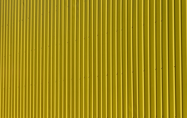 Bright texture of vertical metal siding painted yellow.