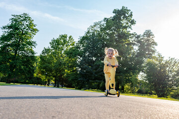 Girl on scooter. Riding child outdoor fun. Sunshine road freedom lifestyle.