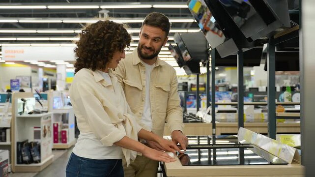 Couple choosing induction stovetop in electronics store