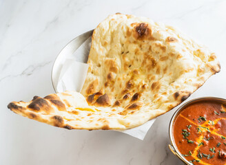 Chicken Tikka Butter Masala with Naan Bread isolated on marble background side view of Pakistani...