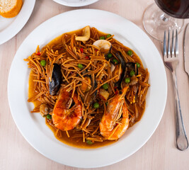 Ready-to-eat seafood paste. Portion of sea pasta cooked with seafood is served on plate. Dish contains prawns, shell mussels, spices and white sauce.
