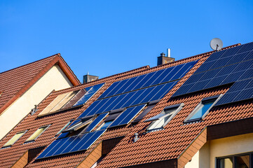 Wohnhausd&auml;cher mit Solaranlagen vor blauem Himmel