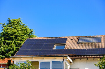 Solardach f&uuml;r solare Stromerzeugung und Warmwasser vor blauem Himmel 
