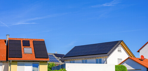 Solaranlagen auf Hausdächern vor blauem Himmel