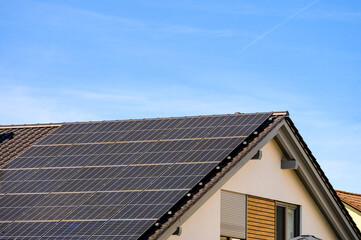 Obraz premium Solarzellen zur Stromerzeugung auf dem eigenen Hausdach vor blauem Himmel