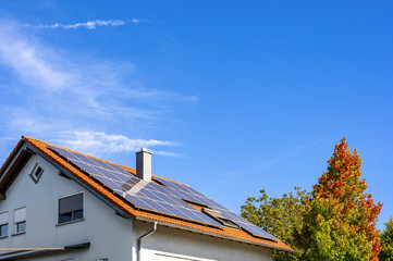 Einfamilienhaus mit Solaranlage vor blauem Himmel im Herbst