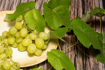 Bunch of grapes, a beautiful bunch of grapes placed on a plate on a rustic wooden surface, selective focus.