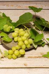 Bunch of grapes, a beautiful bunch of grapes placed on a plate on a rustic wooden surface, selective focus.