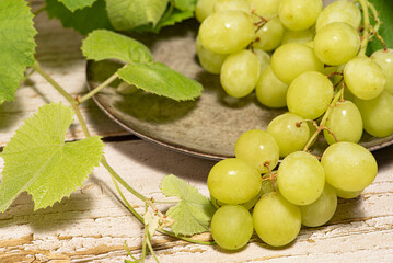 Bunch of grapes, a beautiful bunch of grapes placed on a plate on a rustic wooden surface, selective focus.