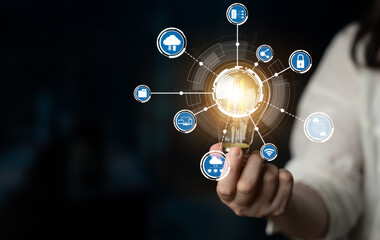 This image depicts a light bulb held by a person hand, surrounded by digital icons symbolizing smart technology and connectivity, representing innovative solutions for the future. Crux
