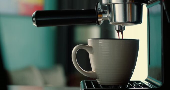 Pouring coffee stream from machine into cup. Fresh espresso brewing with filter holder. Morning ritual of drinking hot black roasted coffee in 4K.