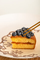 Tweezers Adjusting Blueberries on Cake Slice
