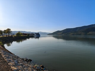 River promenade with docked cruise ship and mountains in the background