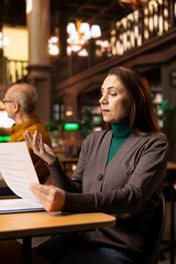 Studious elderly woman prepares research documents in a study room at college, highlighting the intellectual passion of adult learners and her journey through academic life. Coursework.
