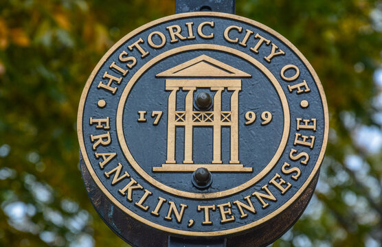 Franklin, USA - October 29, 2023: Closeup of the official seal of Historic City of Franklin, Tennessee, on.black and gold emblem mounted outdoors with blurred autumn foliage in the background