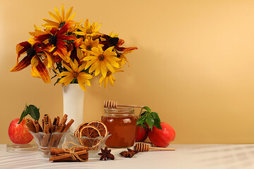 Autumn banner with a beautiful bouquet of rudbeckia in a vase, honey, apples, pomegranates, cinnamon and star anise on an elegant background, autumn greeting and Thanksgiving concept,