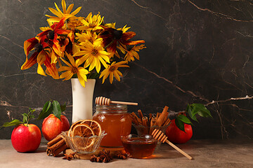 Autumn greeting and Thanksgiving concept, Autumn banner with a beautiful bouquet of rudbeckia in a vase, honey, apples, pomegranates, cinnamon and star anise on a dark background, a