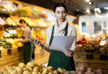 Woman owner of greengrocer, checks financial statements. Upset manager reads documents, calls outsourced accountant for advice.