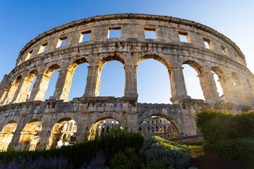 Early morning, sun illuminates stone walls of ancient Roman amphitheater in Pula, Croatia. Tourist attraction, heritage of Roman Empire..