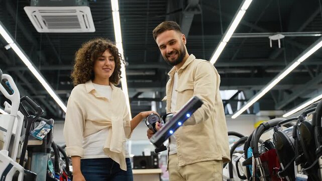 Couple choosing cordless vacuum cleaner in electronics store on Black Friday
