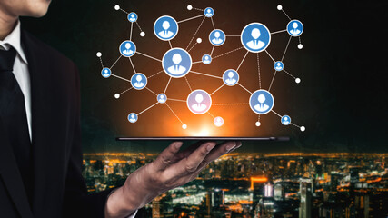 A business professional showcases a tablet featuring interconnected user icons against a city skyline backdrop, symbolizing modern communication and networking innovations. Tessel