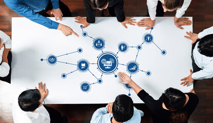 A diverse team of professionals collaboratively engages in a strategy session around a table, analyzing data insights highlighted in a modern office environment. Amity