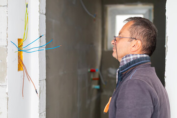 Man electrician performs installation work. Design concept, electronics and engineering. Electrical upgrade, improvement of home.