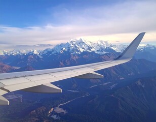 Airplane wing over snow-capped mountains