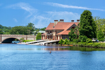 Obraz premium Serene summer day on the Charles River with a lone sculler near a Harvard boathouse in Cambridge, Massachusetts, USA
