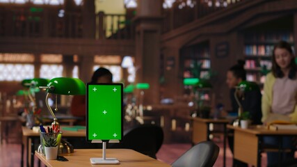 Diverse students and tutors consulting academic materials next to isolated mockup at the school library, reading literature from the database. Scholars complete their class notes. Camera B.