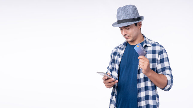 Traveler man holding credit card, mobile phone on white background. Handsome young men with hat and camera showing gadget plastic card with smartphones transaction cashless banking online in travel.