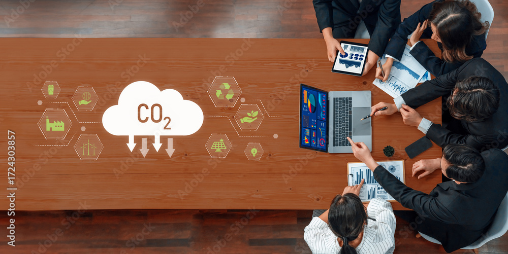 Poster a top-down view of a business team discussing co2 emissions analysis using laptops and charts on a w