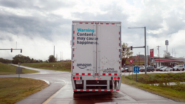 Amazon semi-trailer with sign: Warning content may cause happiness. Truck transporting Amazon products.