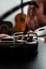 Plugging Cable into Electric Guitar close-up. Jack cable is plugged into the black electric guitar, activating its signal path for rich tones and stage-ready sound.