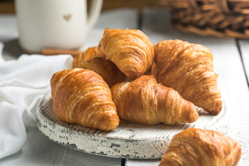 Fresh croissants on white wooden boards, flaky buttery pastry, rustic breakfast