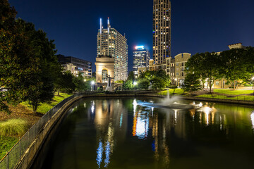 Obraz premium Illuminated arch monument in Atlanta at night with city buildings in background