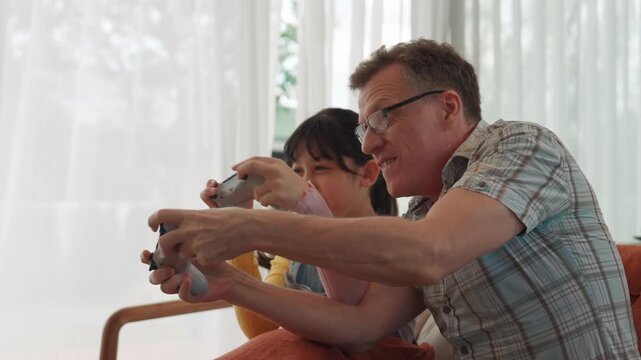 Grandfather and granddaughter together play console game, entertainment media. Old senior use technology communicate with new generation kid cross generation gap strengthen family bond. Divergence.