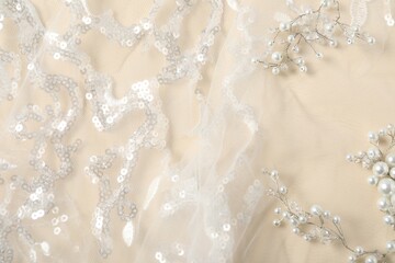 Beautiful lace fabric with sequins and pearls on beige background, flat lay