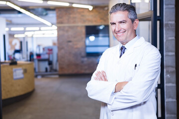 Doctor wearing white lab coat standing by glass partition at reception desk with exposed brick wall