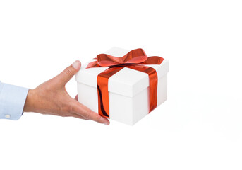 Fototapeta premium Hand holding white gift box with glossy red ribbon and bow in plain white studio