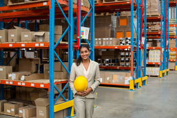 Operations manager inspecting blue and orange storage racks in warehouse and holding safety helmet