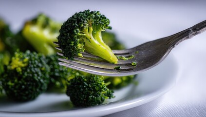 Forkful of steamed broccoli on a plate
